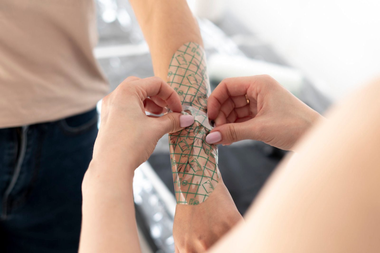 a Close-up hands of master Tattoo artist in black gloves sticking paper with pattern on client's hand